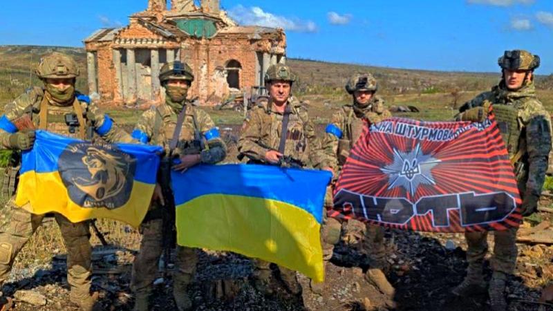 Soldados de Ucrania posando con banderas nacionales alado de una edificación destruida al retomar Klishchiivka. (Foto: AFP)