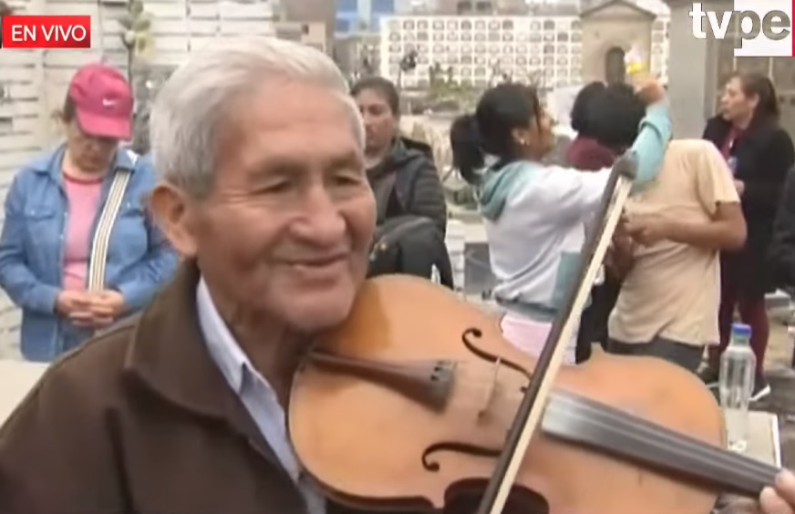Músico tocaba huaynitos en su violín alado del homenaje a fallecidos. Foto captura: Tv Perú Noticias.